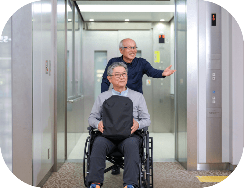 空港内を、車いすの男性を介助し案内している男性の様子