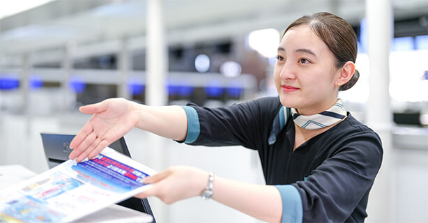 チェックインカウンターで笑顔で案内している女性