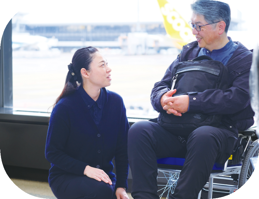 車いすの男性をサポートしている女性の様子。奥には飛行機が見える